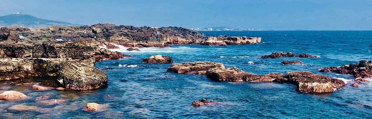 A rocky coastline with clear blue waters and scattered rocks.