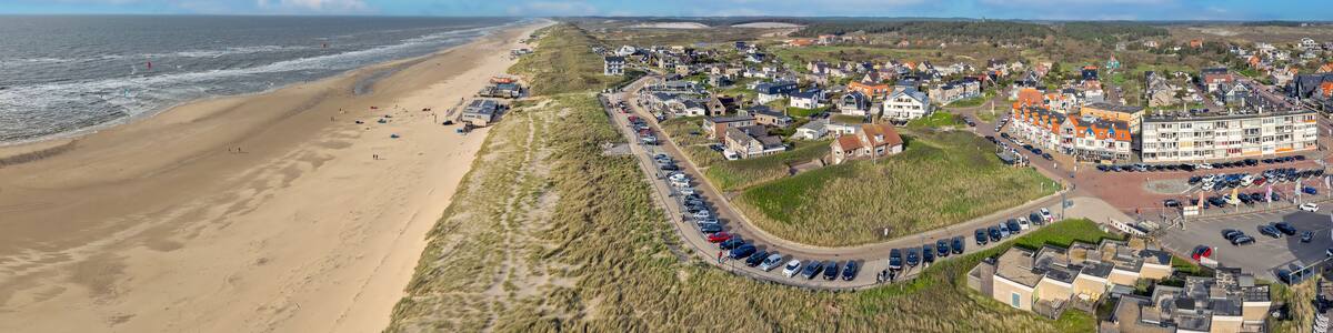 Une ville côtière dotée d’une plage, de dunes et d’un parking.