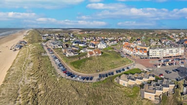 Un pueblo costero con playa, dunas y aparcamiento.
