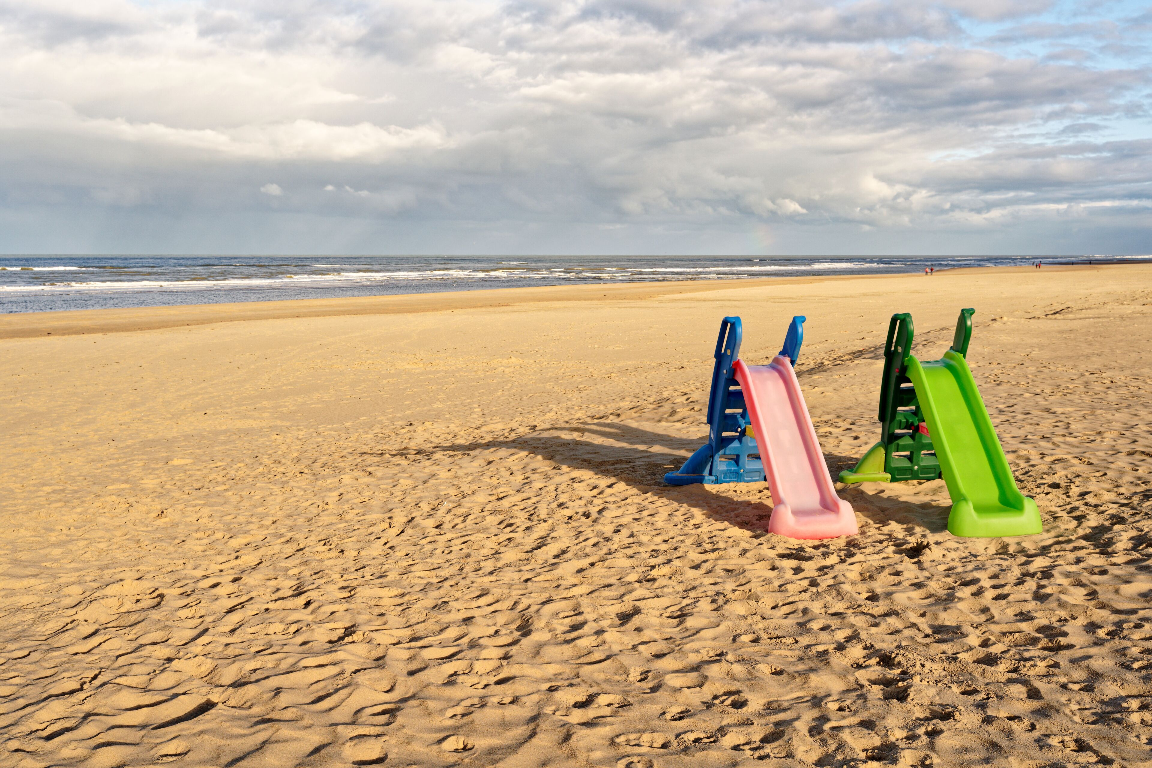 Two colorful playground slides on an almost empty beach. North Holland dune reserve, Egmond aan Zee, Netherlands.