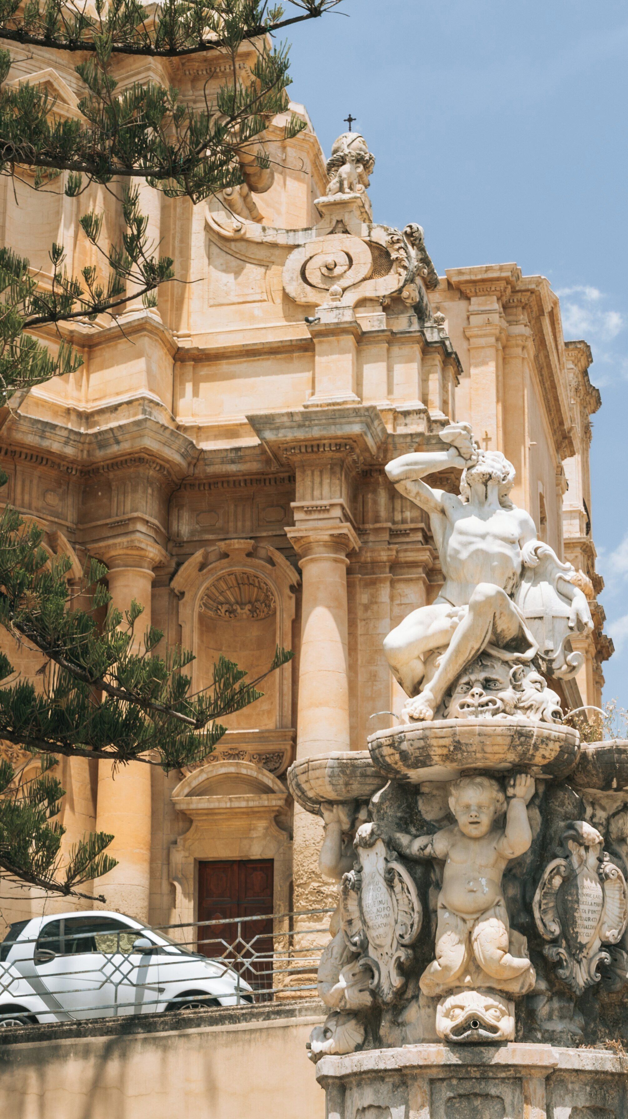 Visit the historic Church of San Domenico in Noto, Sicily, featuring stunning architecture and intricate sculptures under a clear blue sky