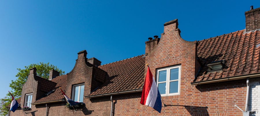 Dutch flag on gable houses in Zevenbergen. Kingsday in The Netherlands