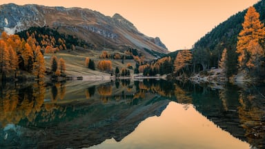 autumn colours and sunrise with reflections in calm mountain lake in the Swiss Alps