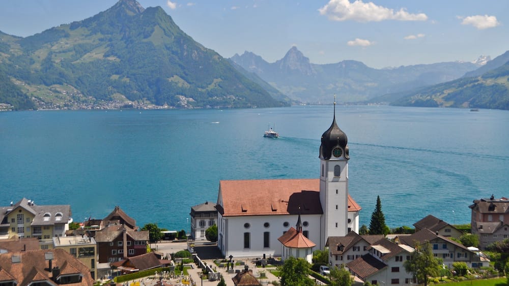 Ein See mit einer Kirche und Bergen im Hintergrund.