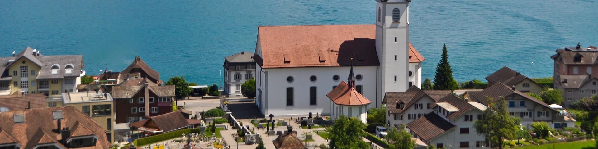 A lake with a church and mountains in the background.