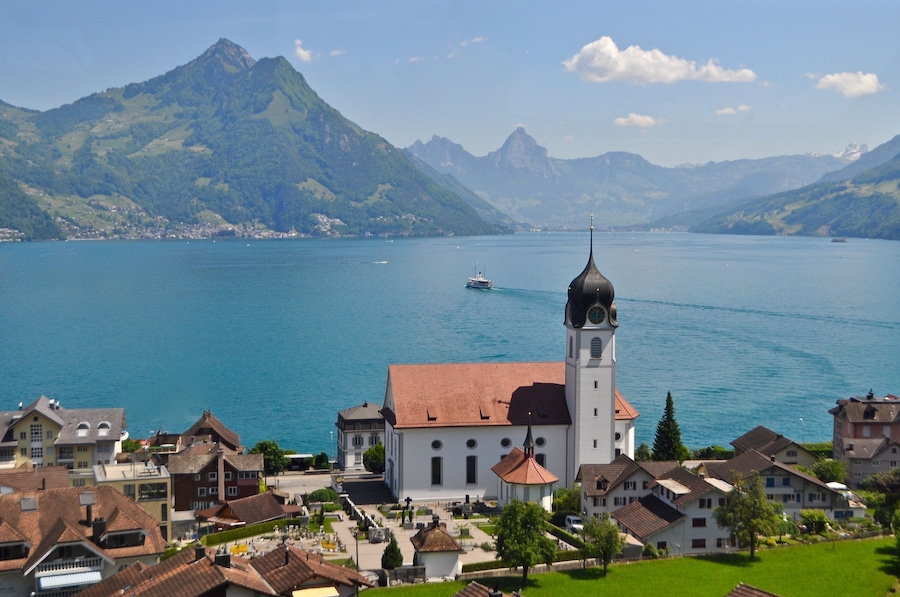 Un lago con una iglesia y montañas al fondo.