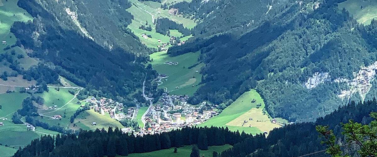 A mountainous landscape with a valley, green fields, and a small town.