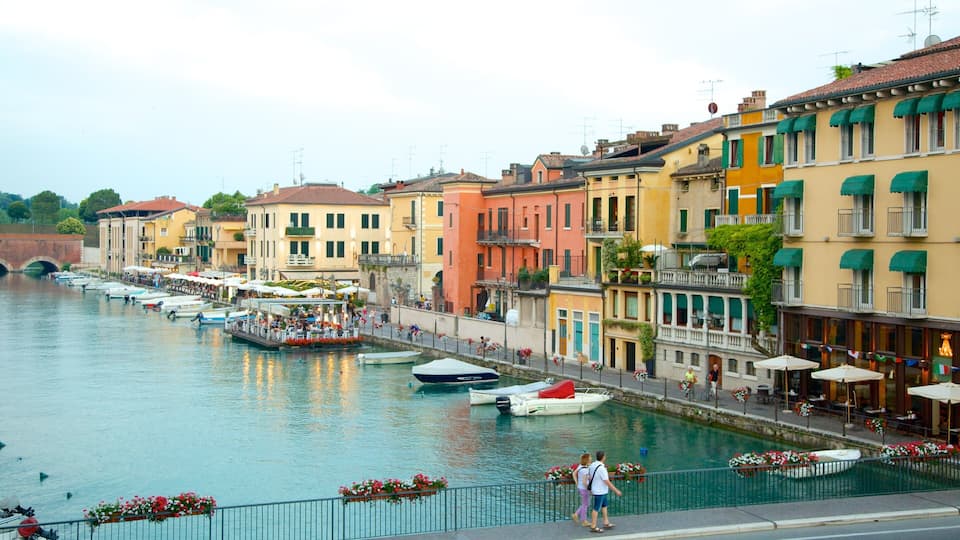 A canal with boats, colorful buildings, and outdoor seating along the waterfront.