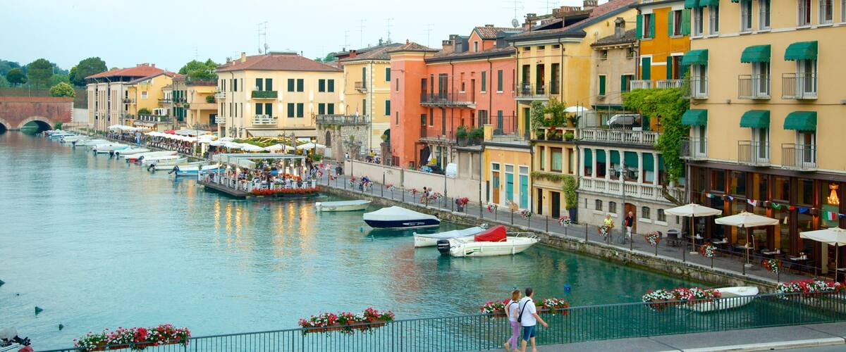 A canal with boats, colorful buildings, and outdoor seating along the waterfront.