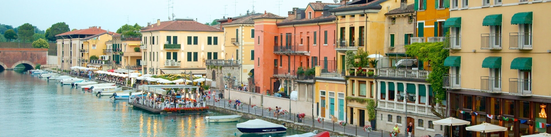 A canal with boats, colorful buildings, and outdoor seating along the waterfront.