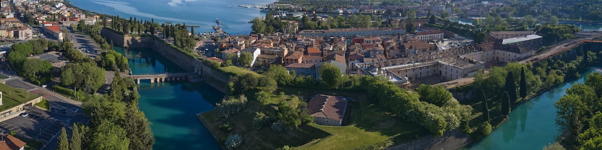 Une ville côtière dotée d’une île fortifiée, d’un fleuve et bordée de montagnes.