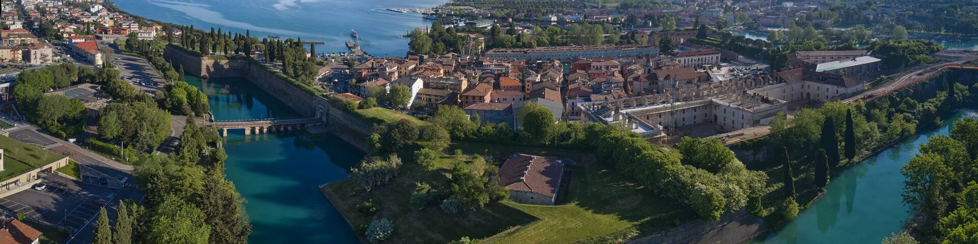 A coastal city with a fortified island, a river, and a mountainous backdrop.