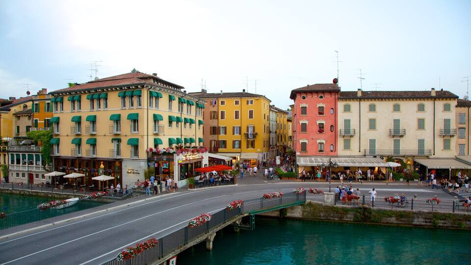 A vibrant street with colorful buildings, a bridge over water, and outdoor seating areas.