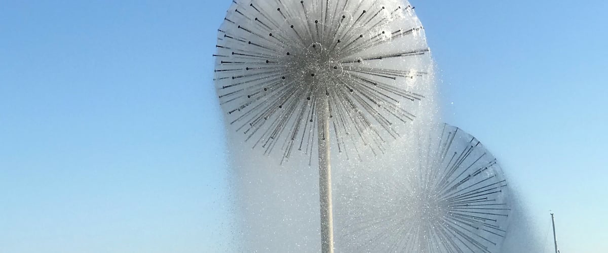 A fountain with multiple water jets and a clear sky.