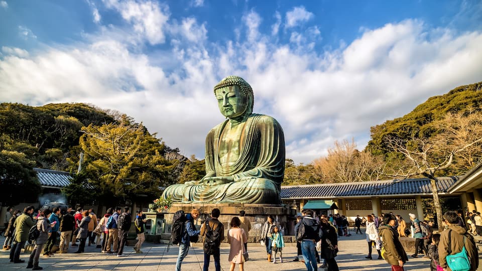 A large Buddha statue surrounded by a crowd of people.