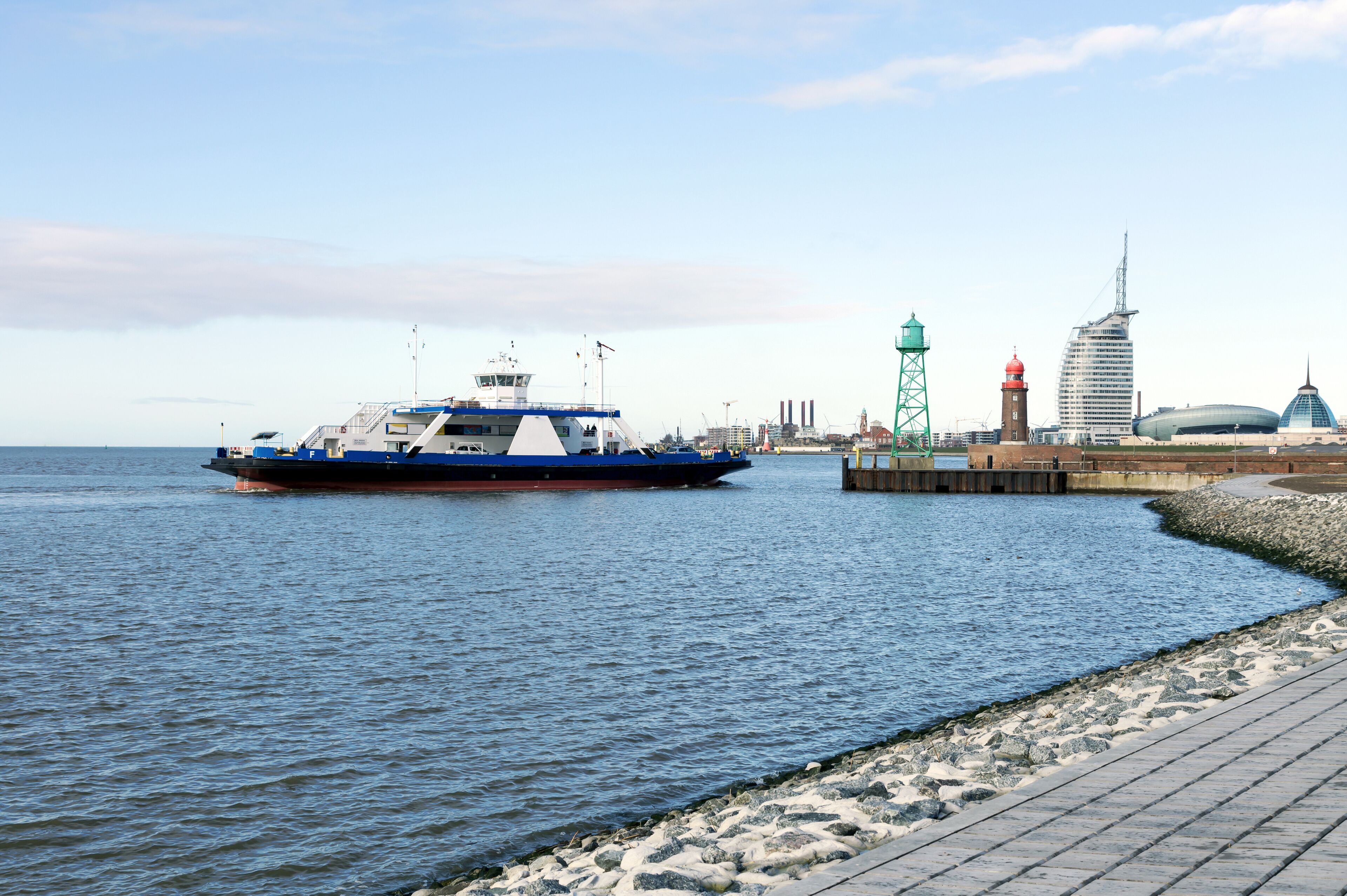 A ferry docked at a pier with a city skyline in the background.