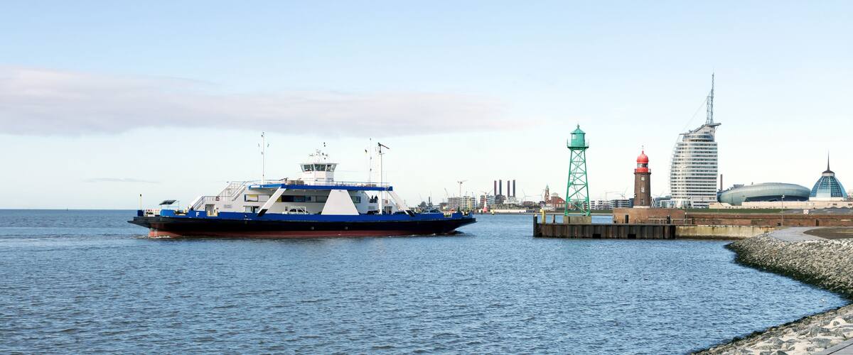 A ferry docked at a pier with a city skyline in the background.