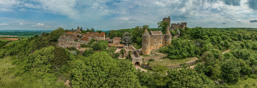 Een historisch kasteel omgeven door weelderige begroeiing en glooiende heuvels.