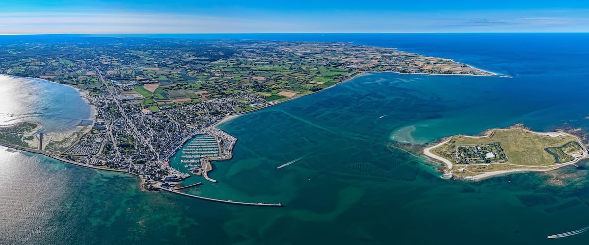 An aerial view of a coastal city with a large bay, a peninsula, and a small island.