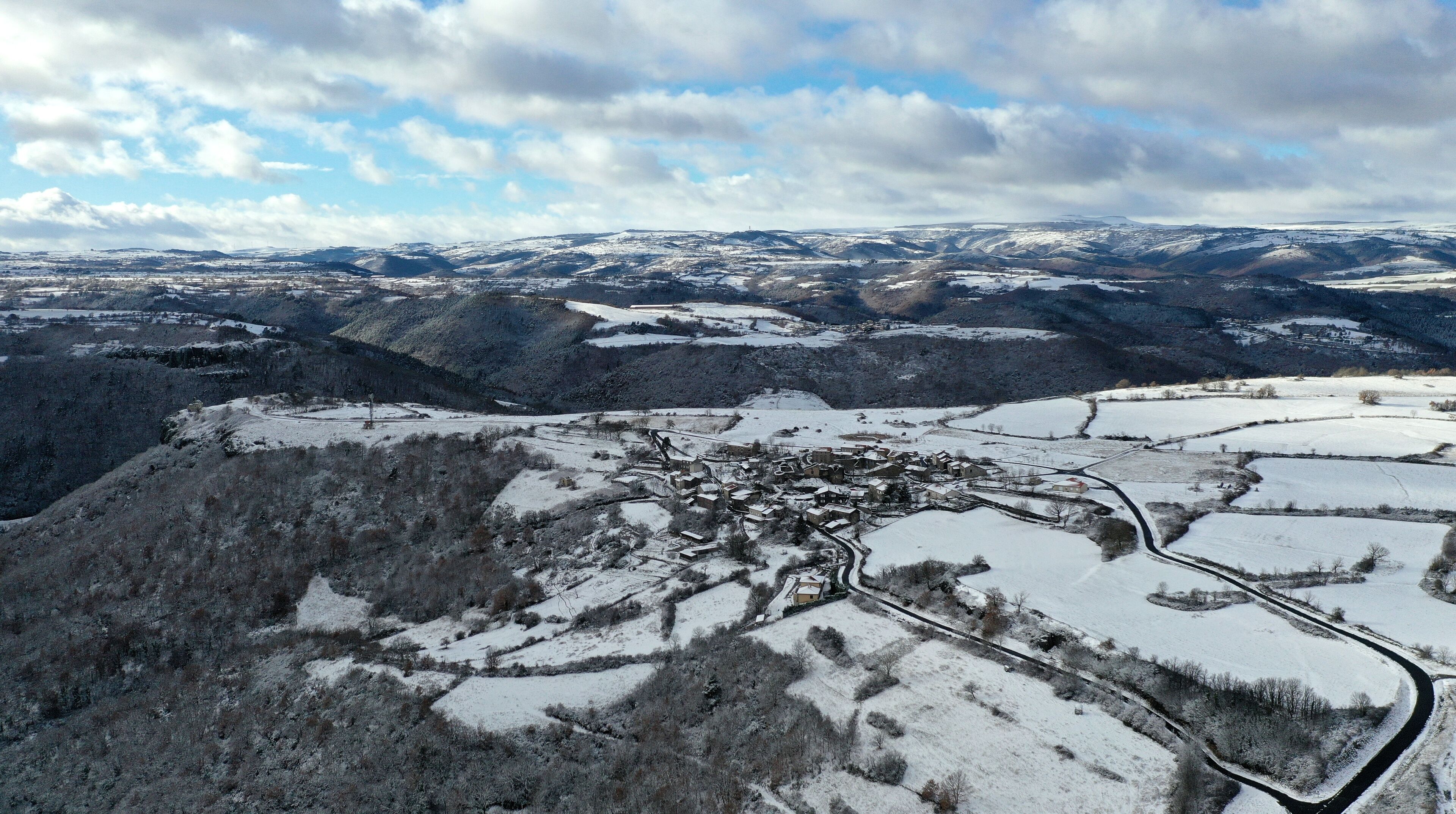 A snow-covered valley with a small town nestled among rolling hills.