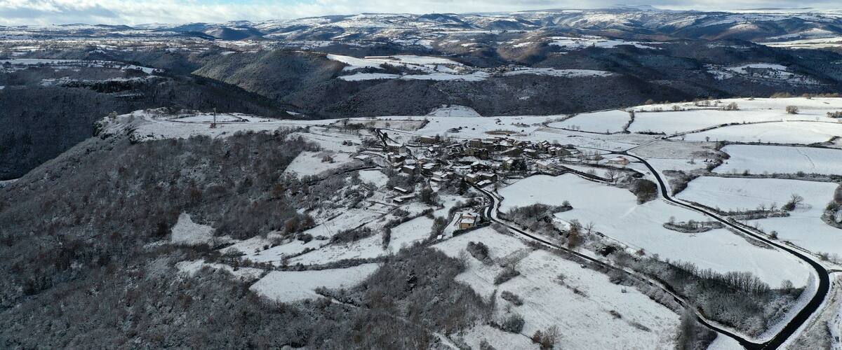 A snow-covered valley with a small town nestled among rolling hills.