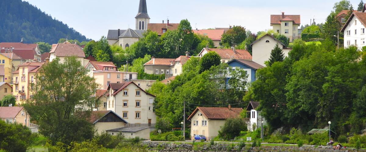 A town with a prominent church steeple, surrounded by colorful houses and lush greenery.