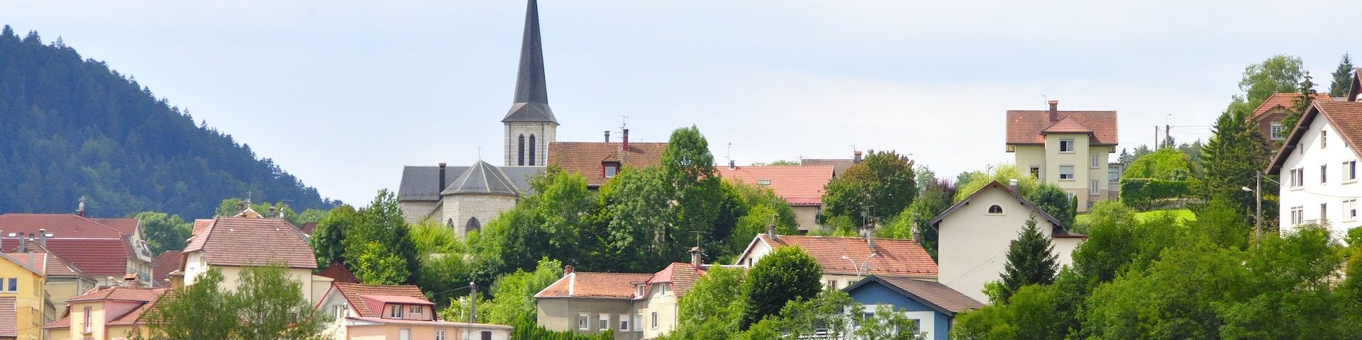 A town with a prominent church steeple, surrounded by colorful houses and lush greenery.