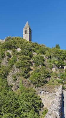 A stone tower on a hill with dense green foliage.
