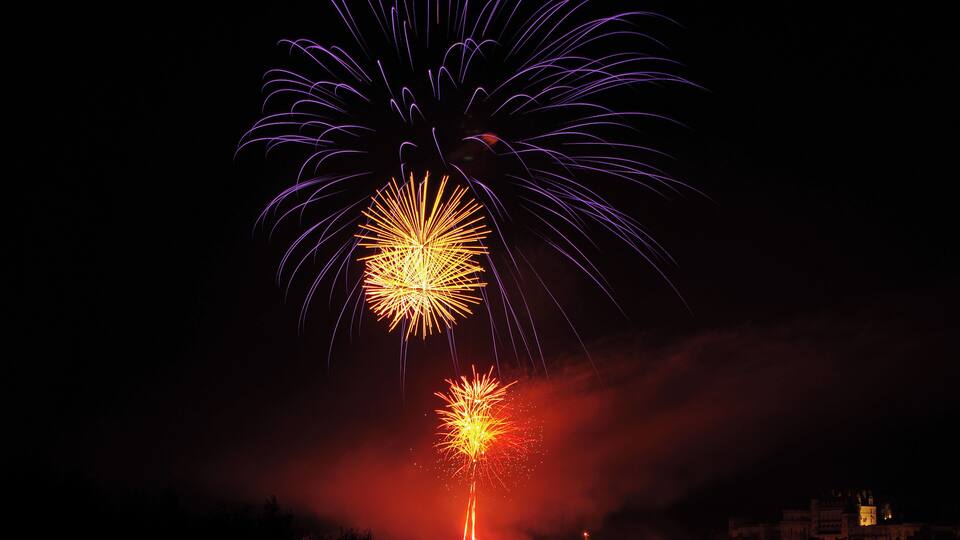 A night sky with fireworks exploding over a cityscape.