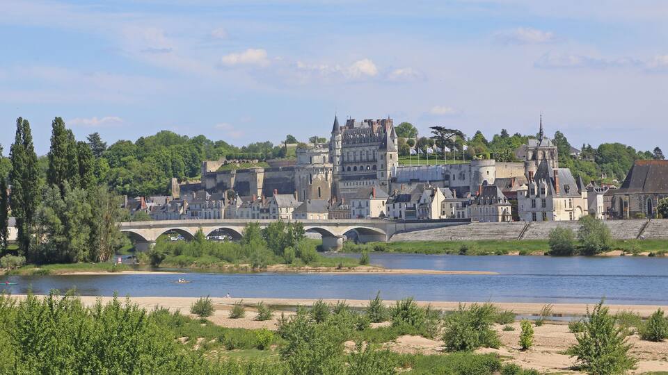 A historic town with a river, a bridge, and a castle-like building.