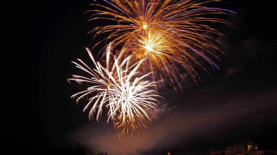 Fireworks over a city skyline at night.