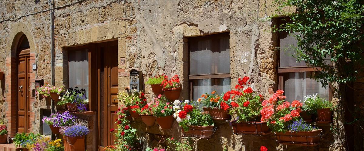 Un edificio rústico con numerosas macetas llenas de flores coloridas.
