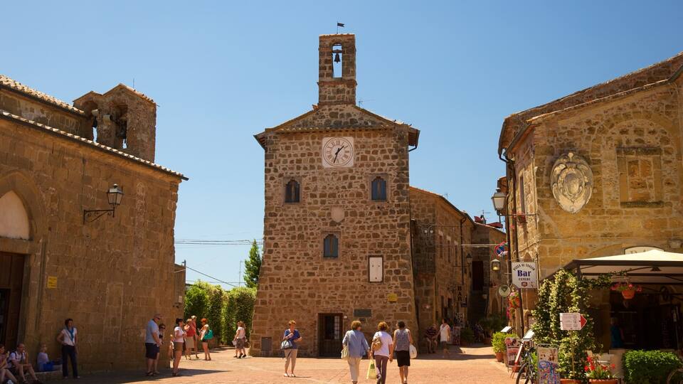 A historic stone building with a clock tower, cobblestone streets, and people walking.