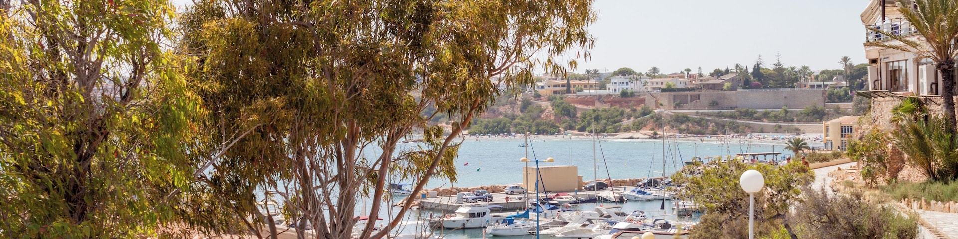A coastal town with a marina, rocky shoreline, and buildings along the sea.