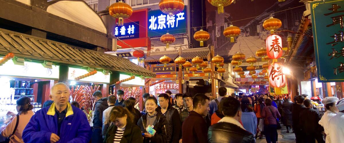 A crowded street at night with traditional lanterns and signs in a foreign language.
