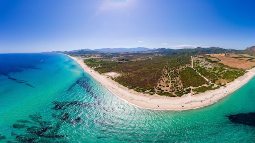 Eine Küstenlandschaft mit Strand, klarem türkisblauem Wasser und einem Bergpanorama im Hintergrund.