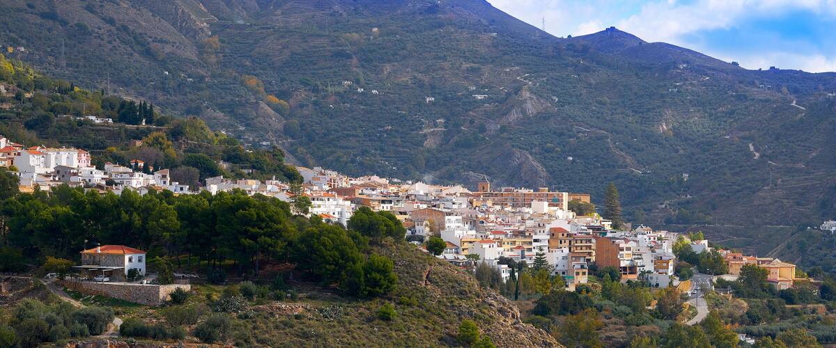 A hillside town with terraced fields and buildings.