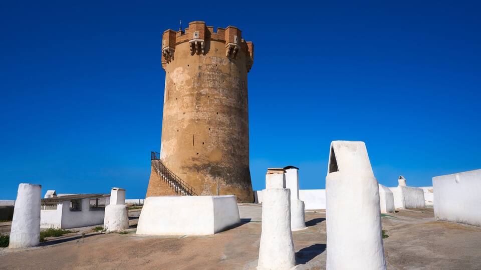 A historic tower with a spiral staircase, surrounded by white bollards.