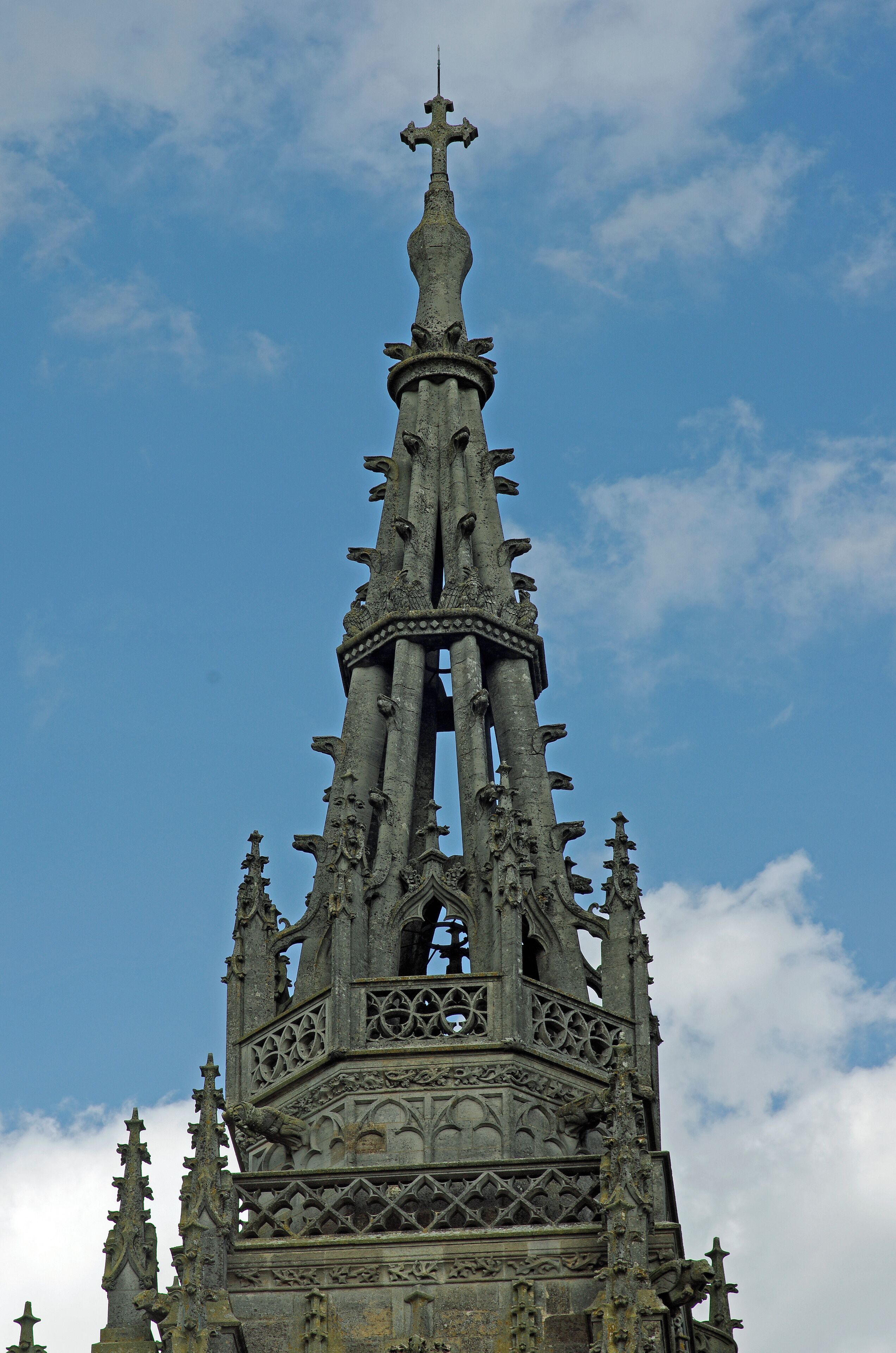 Una torre de iglesia de estilo gótico con intrincados adornos y una cruz en la parte superior.