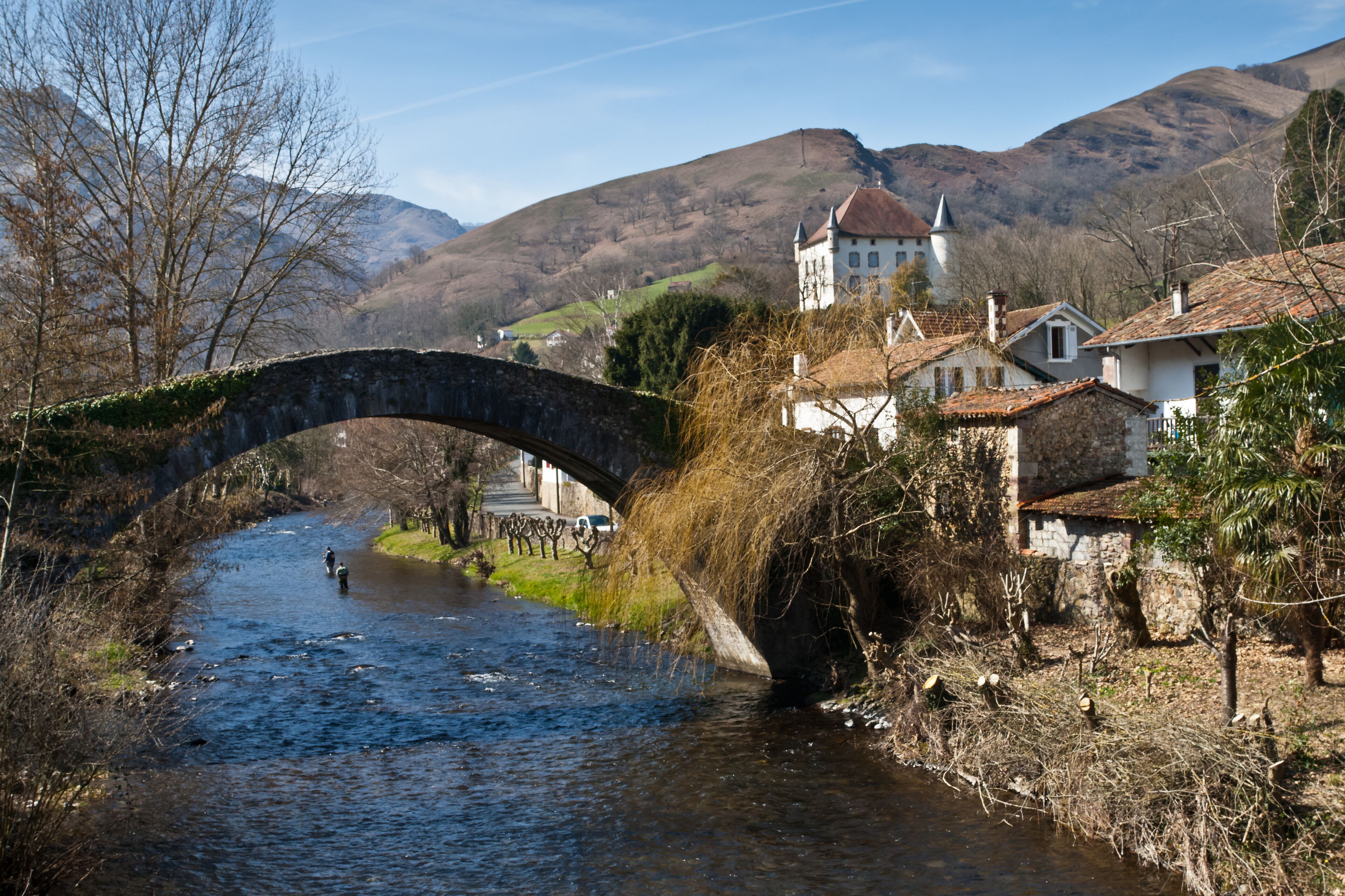 A stone bridge over a river, surrounded by houses and a church.