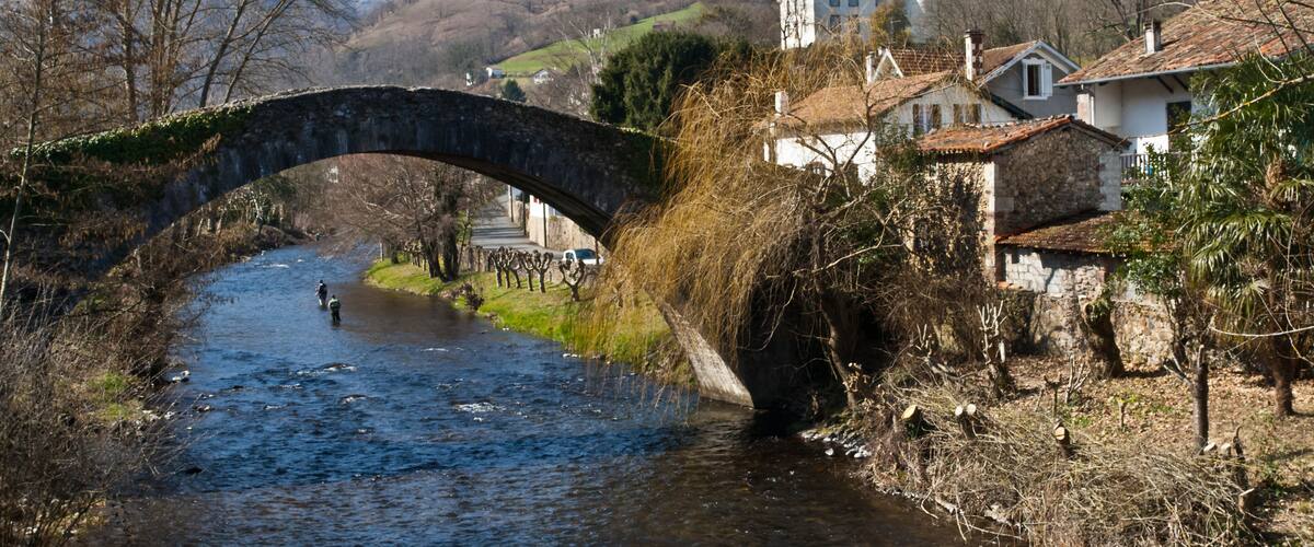 A stone bridge over a river, surrounded by houses and a church.