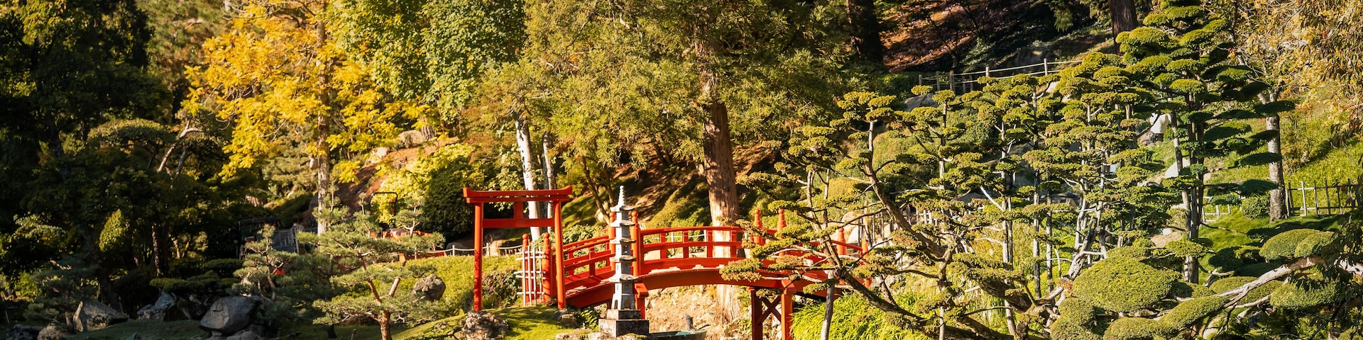 Red wooden crossing bridge over the water in the Botanical Garden in Maulevrier, France