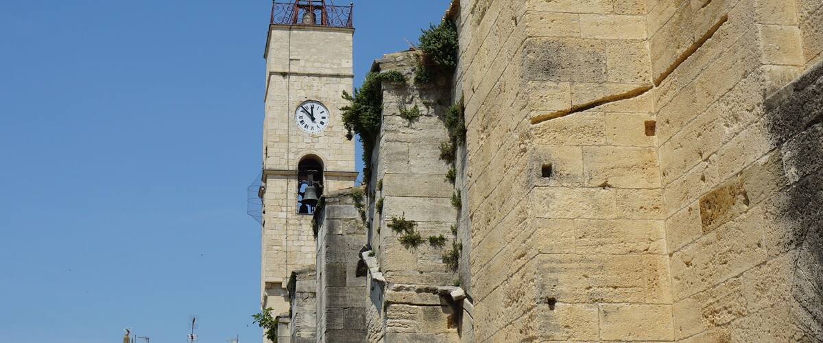 A historic stone tower with a clock and a weather vane.