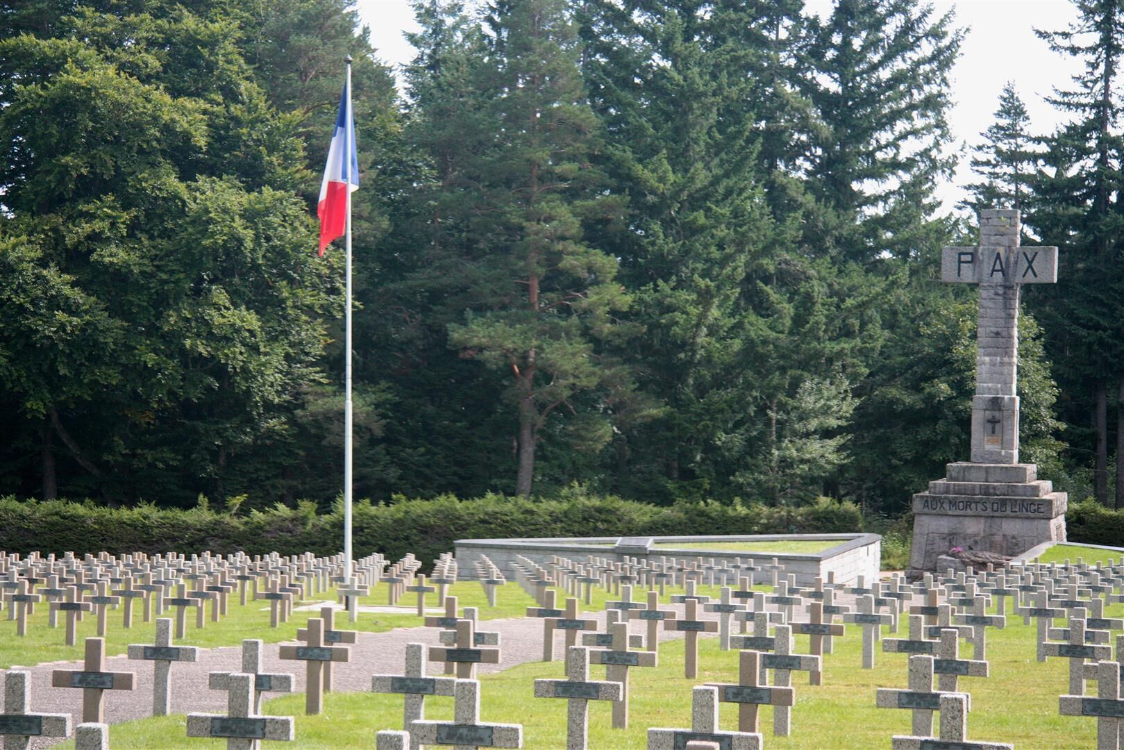 A cemetery with numerous gravestones, a flagpole with a flag, and a monument labeled "PAX".