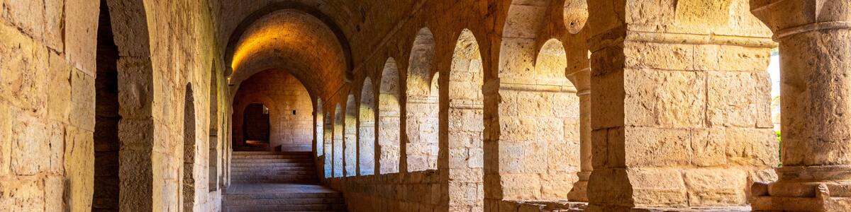 A stone corridor with arches and a central staircase.