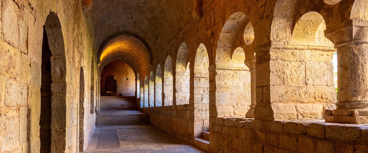 Le Thoronet, Var, France : interior cloister of the Cistercian abbey with stone arches, vaulted ceiling and warm light creating a peaceful architectural perspective