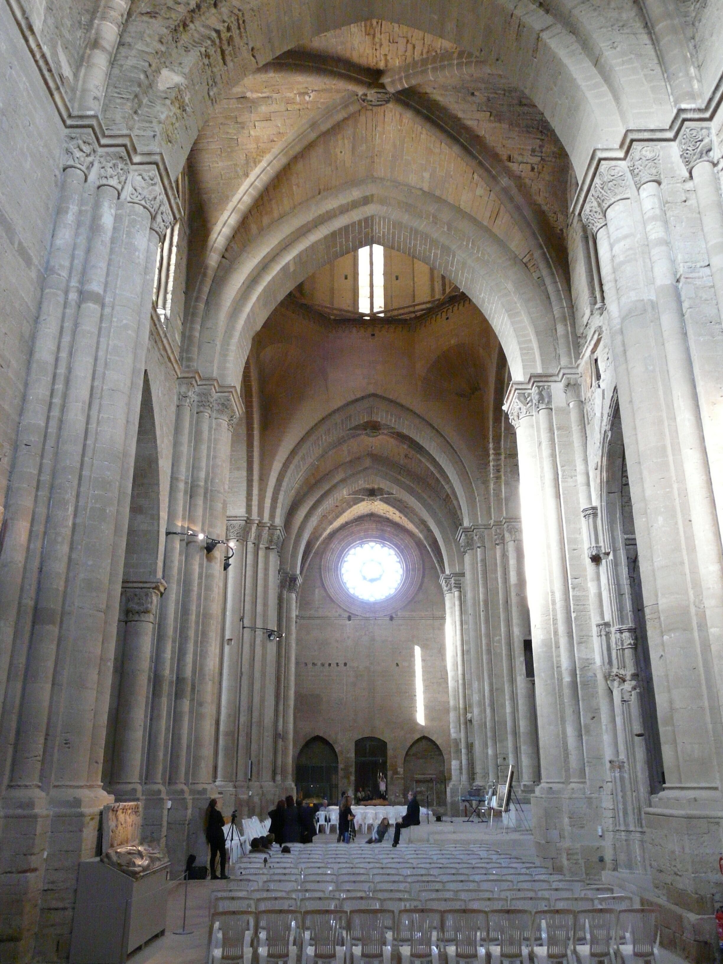 A cathedral interior with high vaulted ceilings, large columns, and a central circular window.
