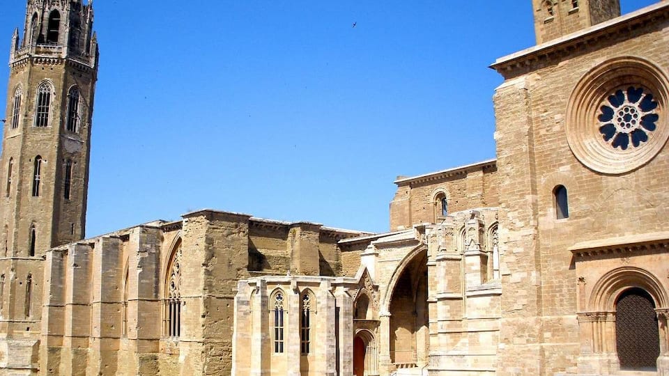 A historic stone building with a tall tower and a large circular window.