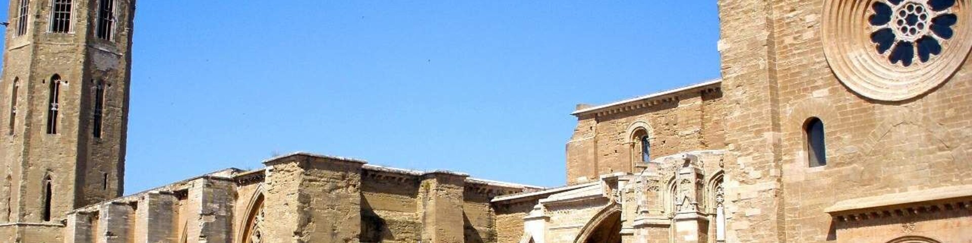 Un edificio histórico de piedra con una torre alta y un amplio ventanal circular.