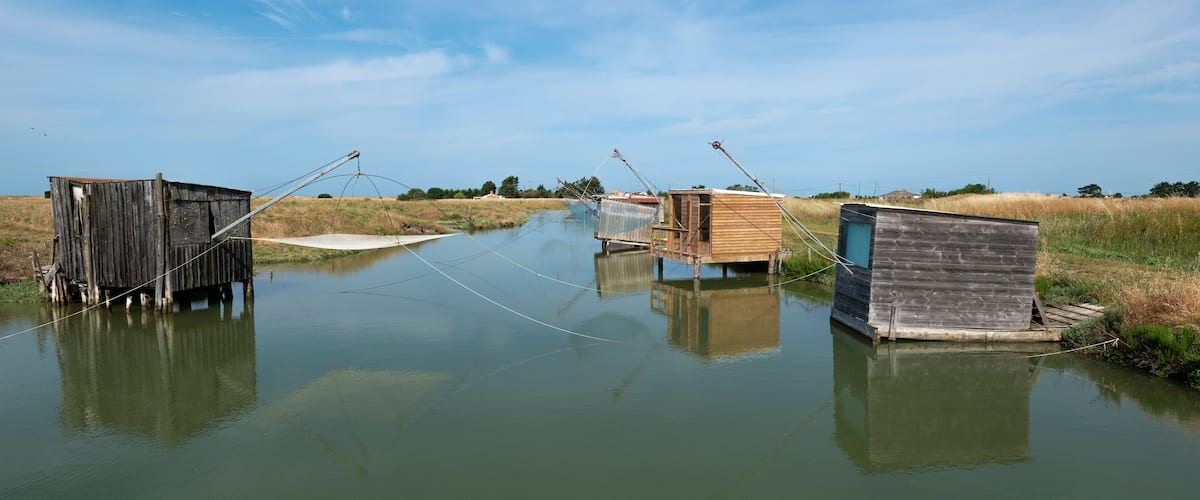 Floating wooden structures on a calm water body with a clear sky.